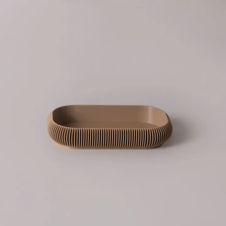 A low oval tray with a ribbed wall, in a sand colour