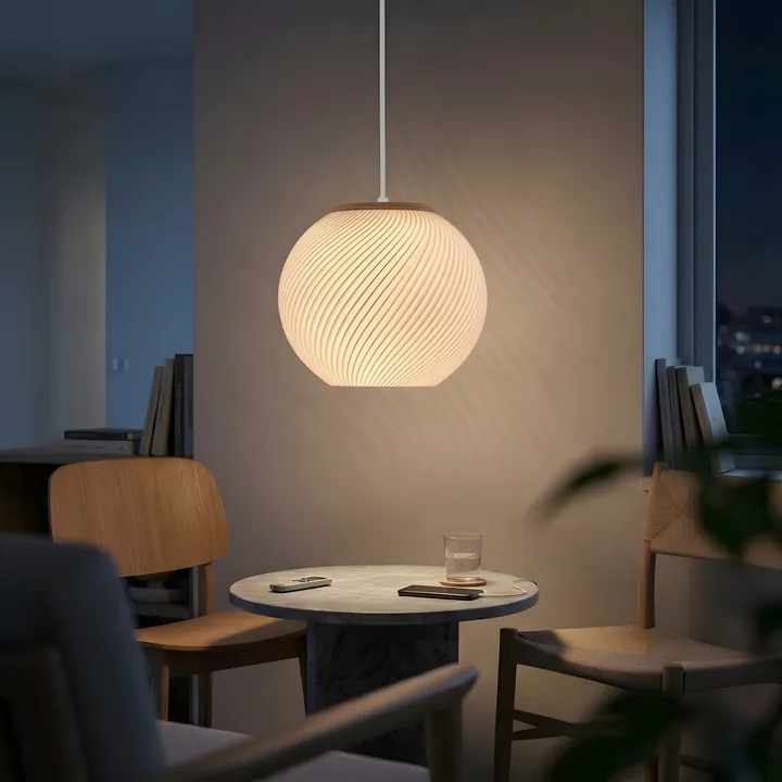 A spiral pendant lit over a small round table in a dining corner at night