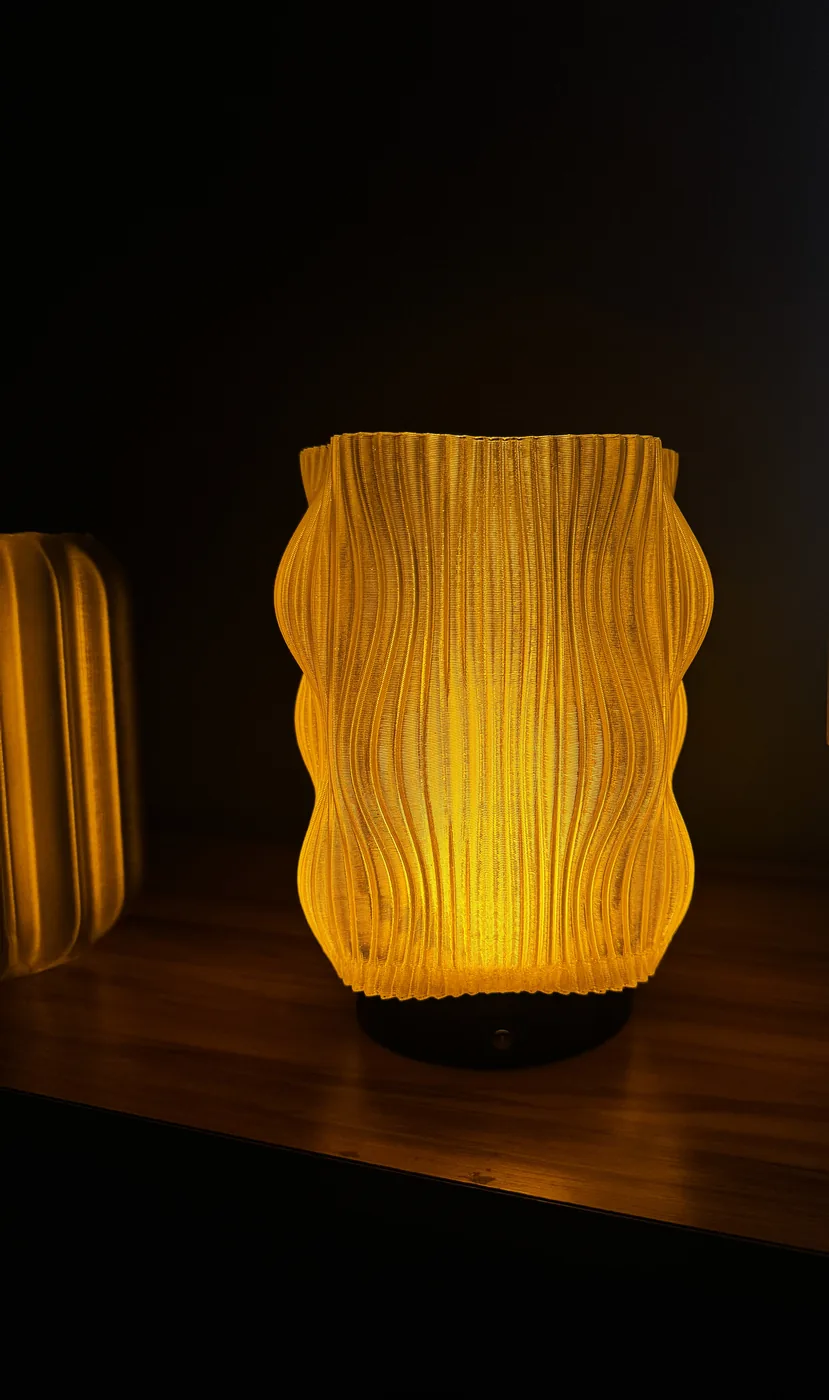 Luminária impressa em PETG âmbar, acesa sobre uma mesa de madeira