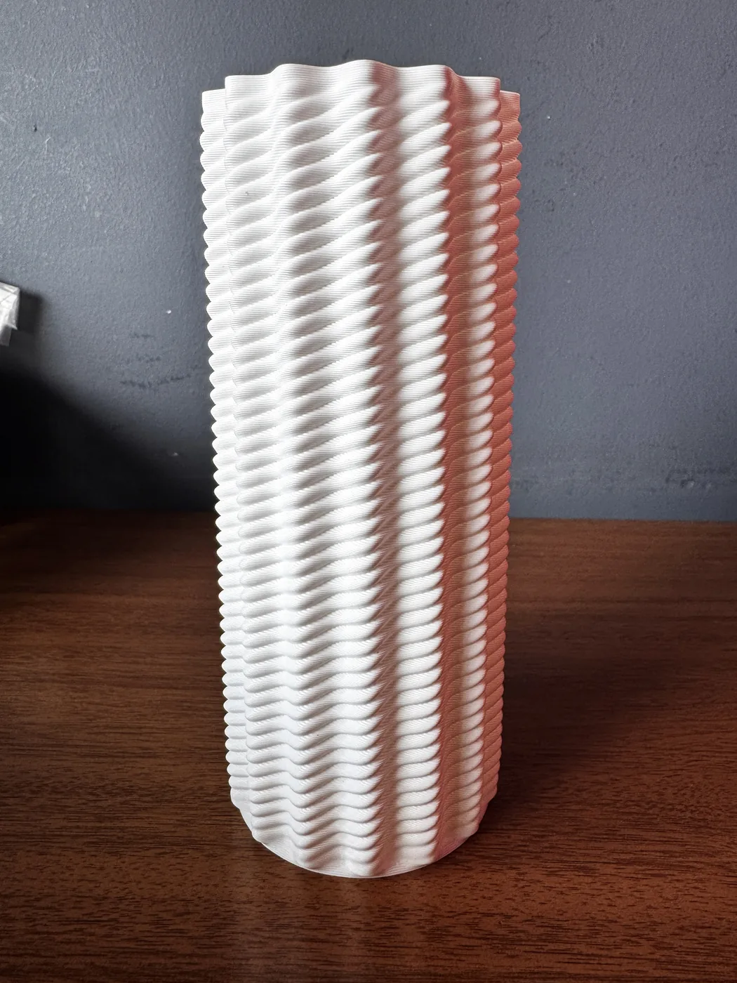 Vaso impresso em PETG branco sobre um aparador de madeira